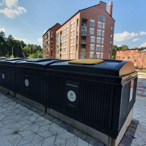 Syväkeräyssäiliörivi, jonka taustalla kerrostaloja, metsää ja vanha korkea tiilipiippu.