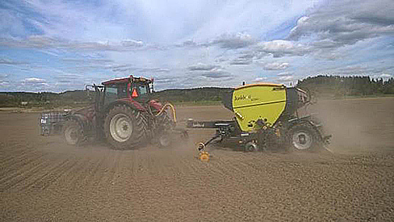 Kierrätyslannoitteiden levitys käynnissä pellolla - traktori vetää perässä laitetta