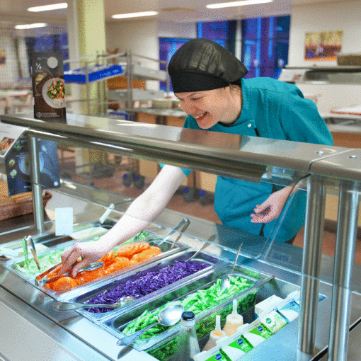 Keittäjä asettaa ottimia ruokalan salaattipöydän astioihin.