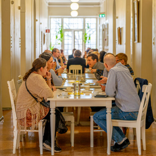 Uudelleenkäytön kevätpäivän seminaarivieraat kahvilla viehättävän Lapinlahden vanhan sairaalarakennuksen aurinkoisella käytävällä.