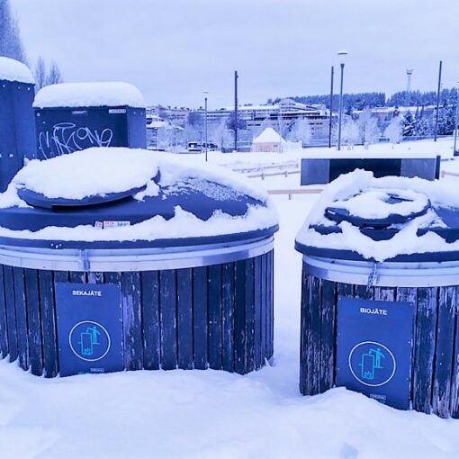 Kuvassa kaksi pyöreää lumen peittämää jätekeräysastiaa