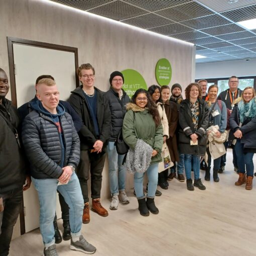 Kuvassa ryhmä opiskelijoita seisoo talvivaatteissa rivissä hymyillen kameralle