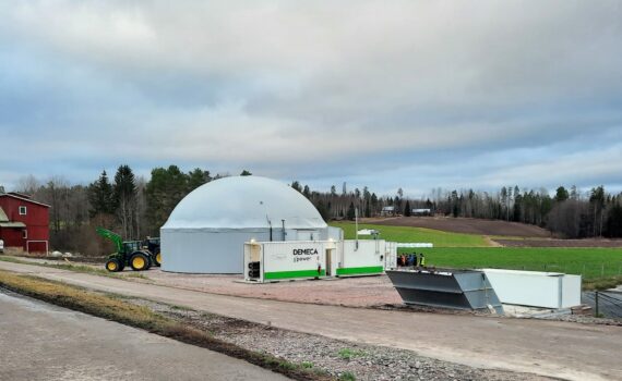 Kuvassa tien vieressä valkoinen pyöreäkattoinen biokaasulaitos, jonka taustalla vihreää nurmea ja metsää