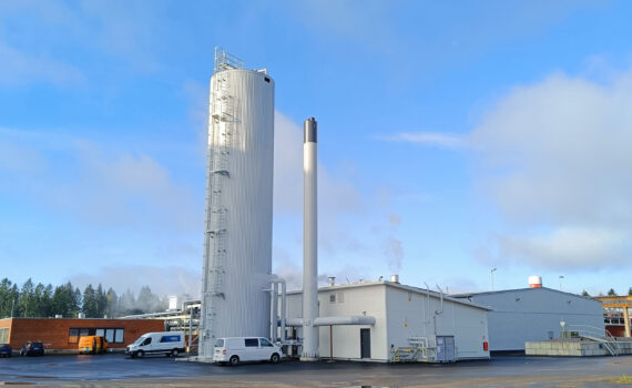 Advenin energialaitos lämpöakkuineen Säkylässä Apetitin pakastetehtaan vieressä. Kuvassa energialaitos ja lämpöakku, jotka ovat valkoinen matala rakennus ja sen vieressä korkea valkoinen torni. Laitoksen pihaan on parkkeerattu kaksi pakettiautoa. Taustalla sininen taivas ja muutama pilviharso.