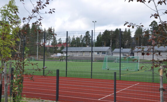 Söderkullan urheilukenttä Sipoossa. Nurmikenttää ympäröi aita ja punainen juoksurata. Kentällä on jalkapallomaali. Taustalla on huoltorakennuksia.