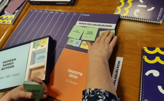 Naisen kädet asettelmassa ilmastopalapeliä pelialustalle.