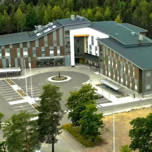 Hollolan uusi suuri L-muotoinen sote-keskus puiden reunustamalla tontilla.