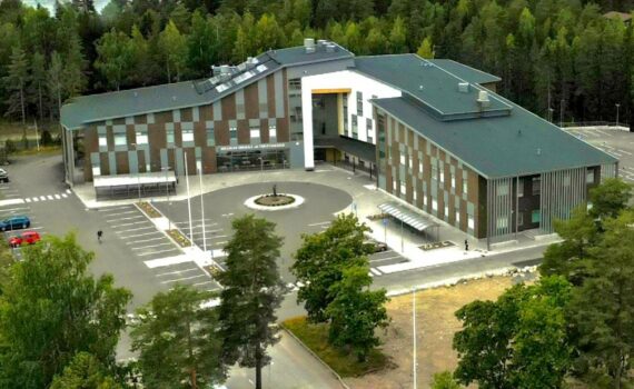 Hollolan uusi suuri L-muotoinen sote-keskus puiden reunustamalla tontilla.