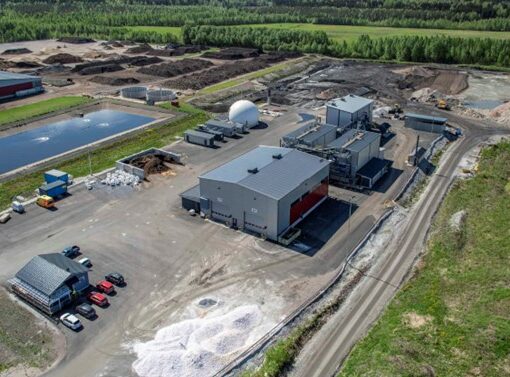 Ilmakuva Kukkuroinmäen jätekeskuksen alueesta, jossa näkyy rakennuksia, valkoinen pyöreä biokaasusäiliö, läjityskasoja ja taustalla metsää.