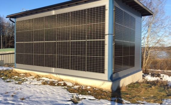 Nikus vedenottamon aurinkojärjestelmä. Kuution mallinen rakennus, jonka näkyvillä sivuilla on aurinkopaneeleja. Maassa on ohut kerros lunta.